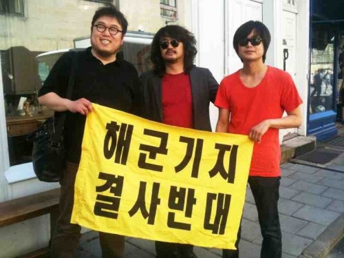 Three-quarters of the Naneun Ggomsuda team display their banner opposing the Jeju naval base
