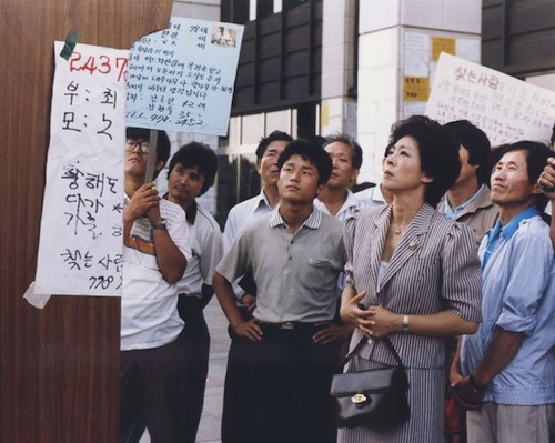 Hwa-young (played by Kim Ji-mee) looks for news of her lost son in KBS Plaza