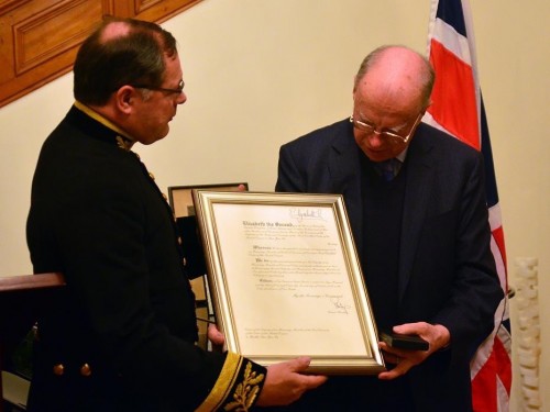 An Sonjae receiving his MBE from Ambassador Charles Hay