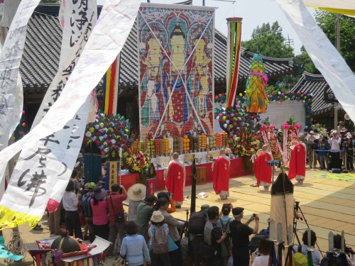 Four monks perform the cymbal dance in front of the painting of the Vulture Peak Assembly