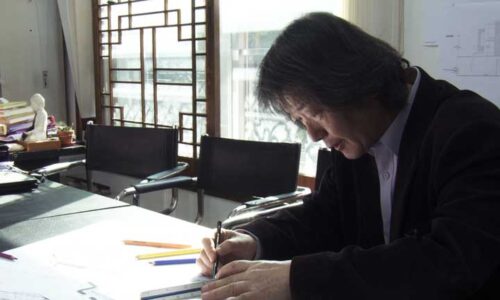 The stooped figure of an architect works on a drawing
