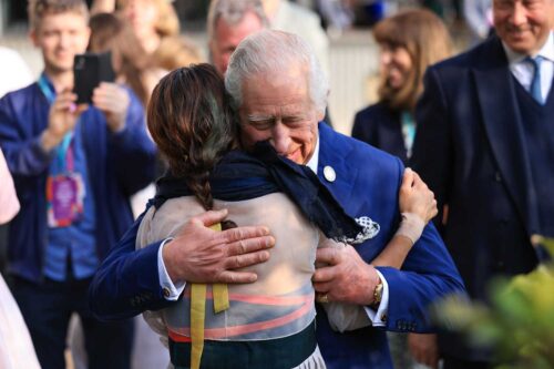 King Charles hugs Jihae Hwang, with a smile on his face