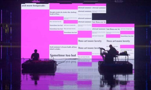 Dark figures of a geomungo player and another musician against a bright pink projected background with words from a Shakespeare sonnet