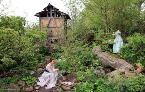 A pastoral scene in front of a rustic herb drying tower