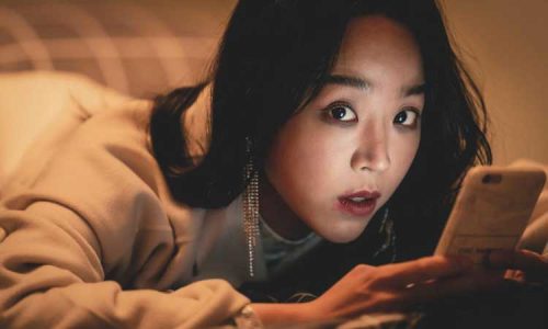 Still from the movie Following (2024) - a woman looking at her phone, scared